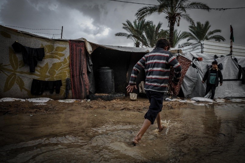 Rainwater between tents beneath a stormy sky in Gaza